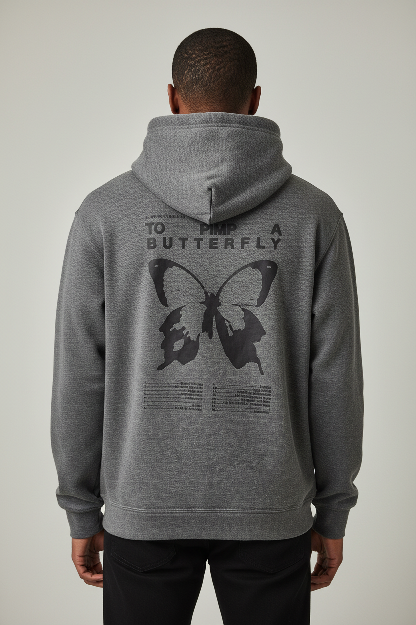 A man viewed from behind wearing a heather gray pullover hoodie with a large black graphic on the back featuring a butterfly and the text 'TO FLOW AS A BUTTERFLY'.