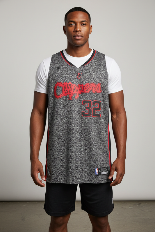 A man modeling a gray Los Angeles Clippers basketball jersey with red lettering and the number 32, worn over a white t-shirt and black shorts against a neutral studio background.