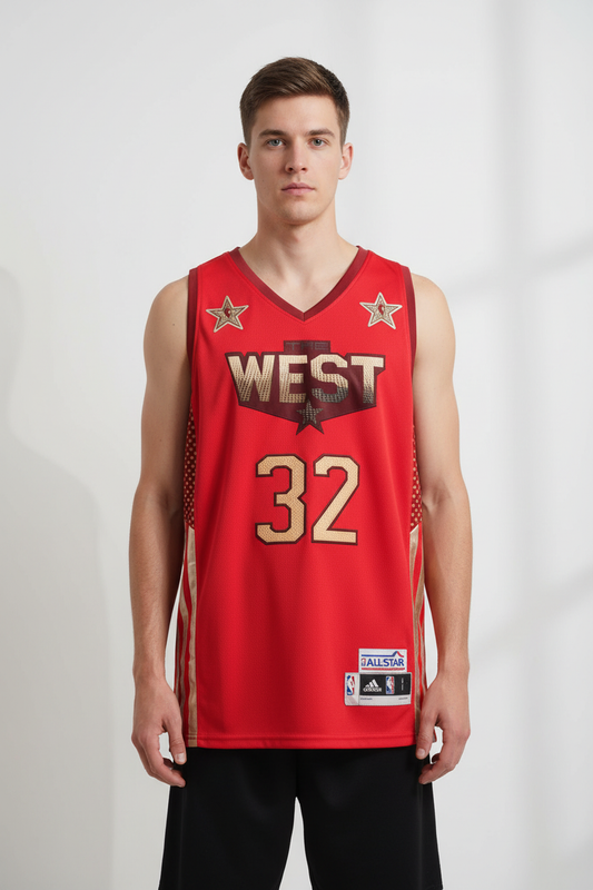 A male model wearing a red Adidas All-Star basketball jersey with 'WEST' and the number '32' in gold, paired with black shorts against a light gray studio background.