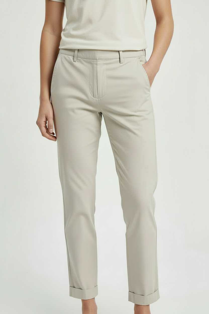 A model wearing light beige cropped trousers with rolled cuffs, paired with a cream-colored top, shown from the waist down against a plain light background.