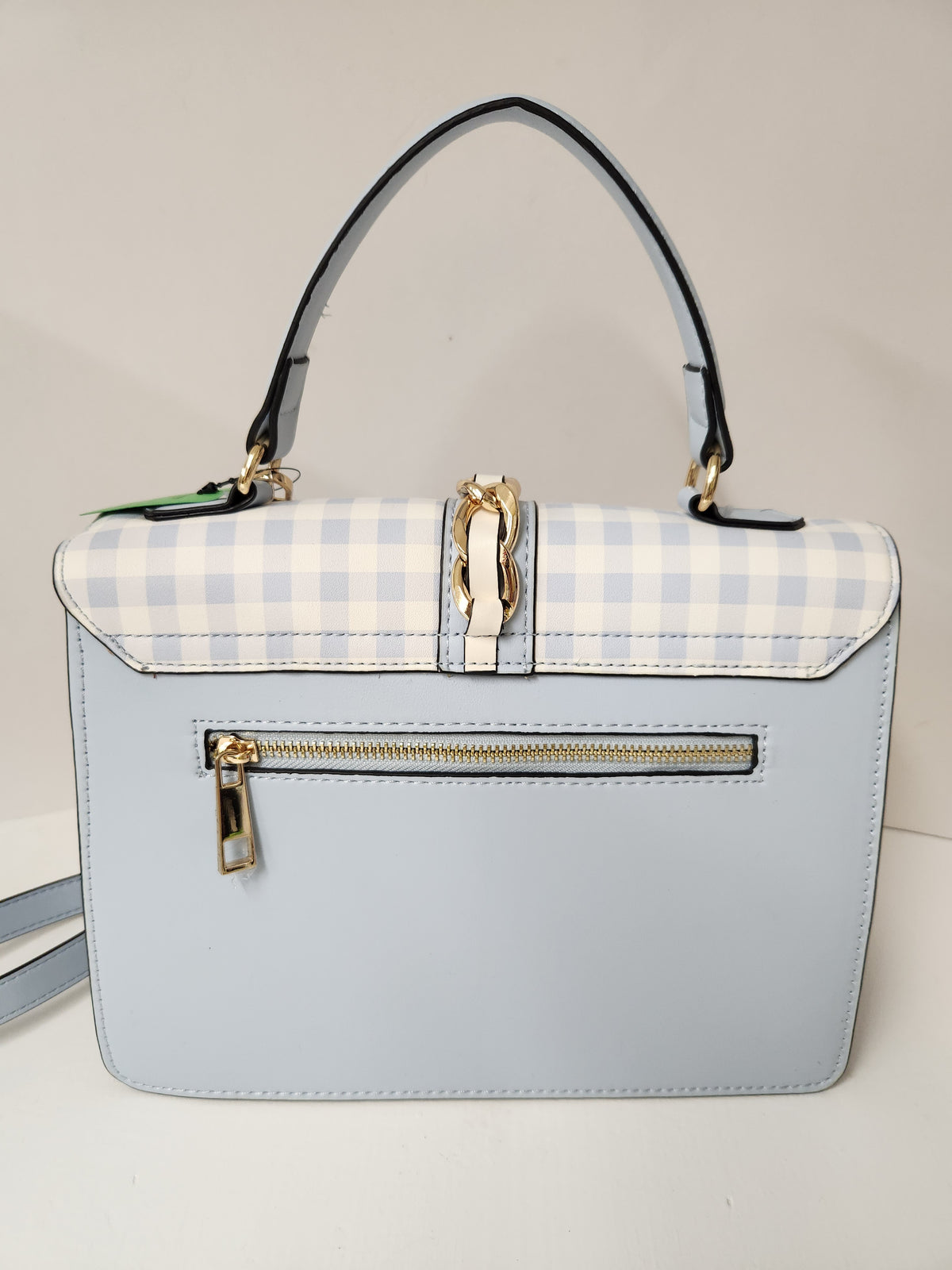 A structured light blue handbag with a light blue and white gingham patterned flap, a central gold-tone horsebit clasp, a front zippered pocket, and a black top handle.