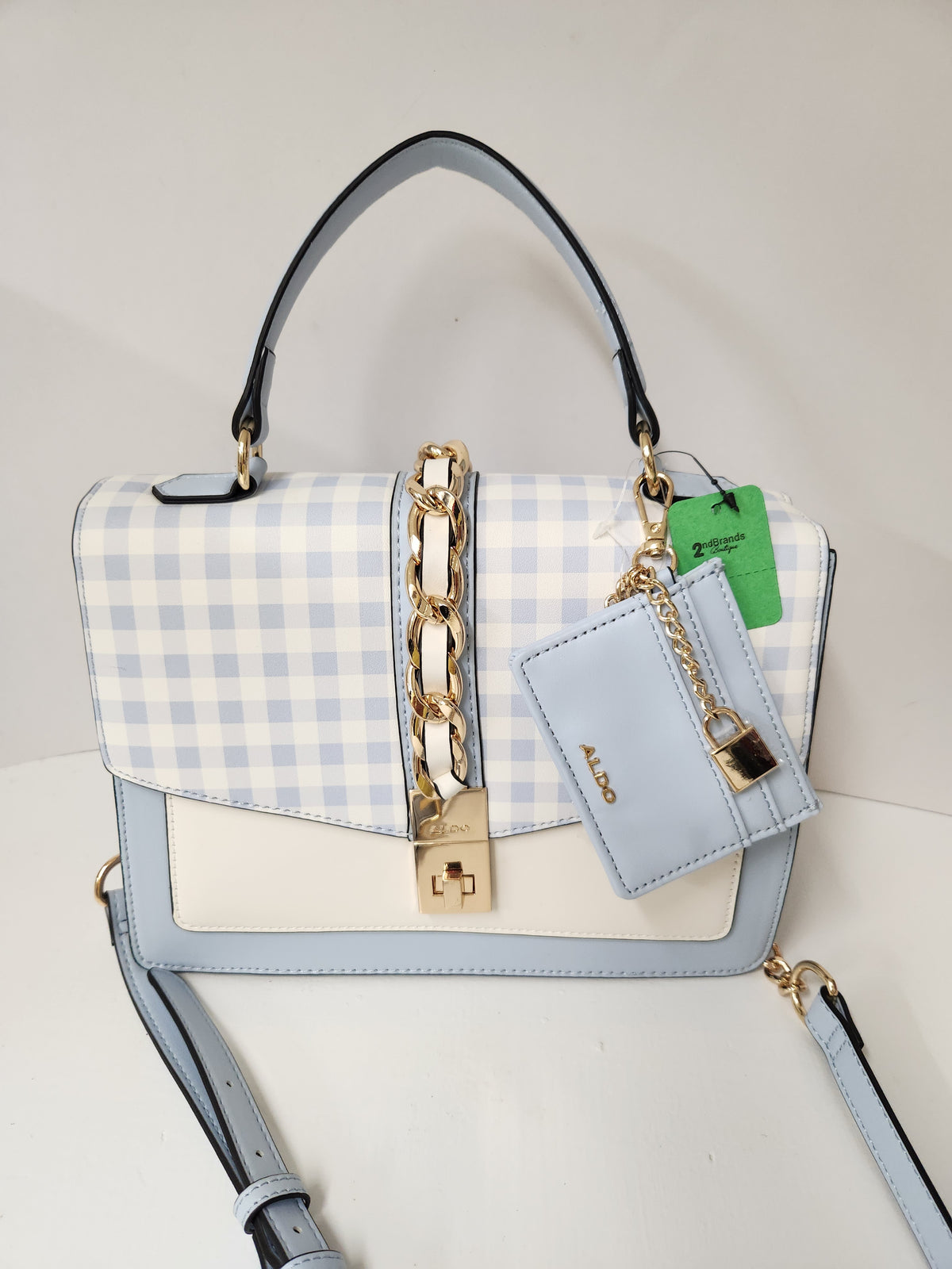 A light blue and white gingham handbag with a pale blue leather body, gold-tone hardware, a top handle, and a matching key pouch with a lock charm. The brand name 'AKO' is visible on the key pouch.