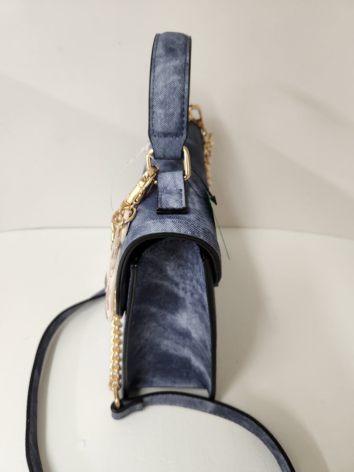 A dark blue velvet handbag with a gold chain strap and gold hardware, shown from a side profile view on a light beige background.