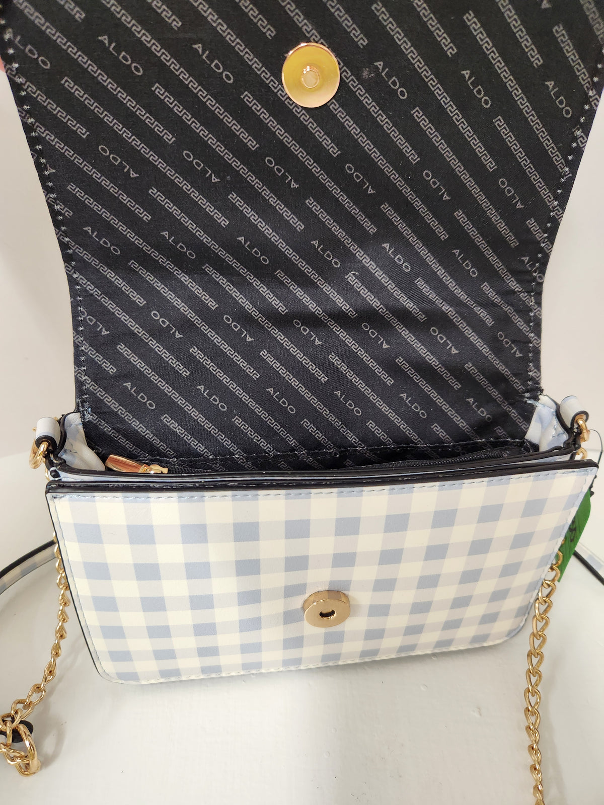 A small Aldo handbag with a light blue and white gingham patterned exterior, a black patterned interior flap, and gold-tone hardware including a chain strap and snap button.