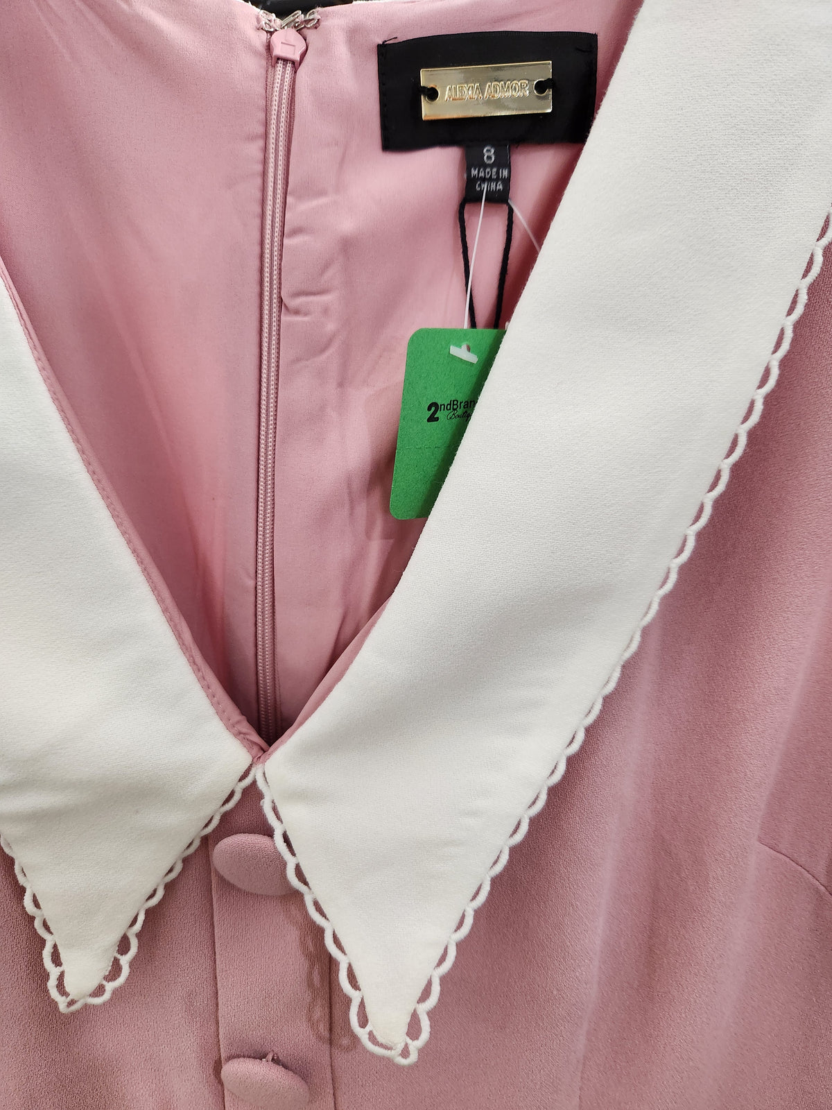 Close-up of a pink garment with a large white scalloped collar and a black brand label reading Miu Miu Paris.