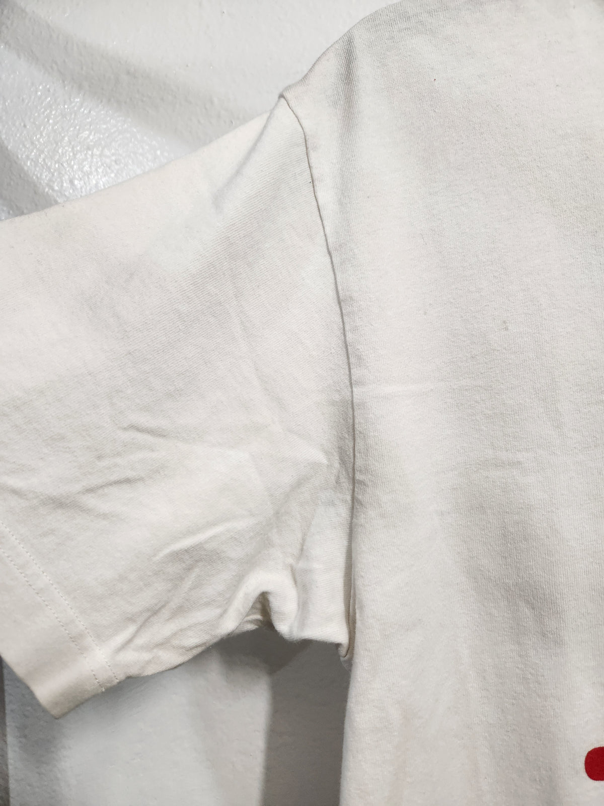 Close-up of a white cotton t-shirt showing the sleeve, shoulder seam, and textured fabric.