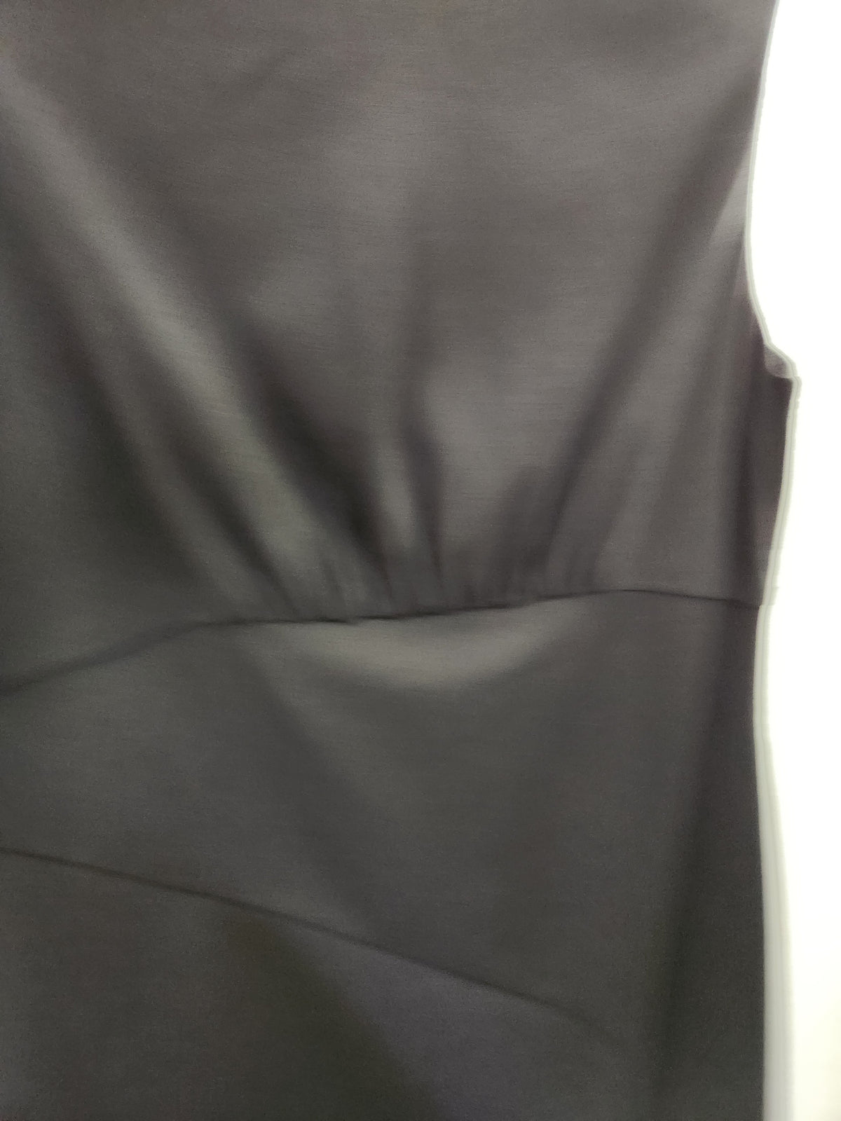 Close-up of a dark charcoal gray sleeveless dress or top fabric, showing the smooth texture and gathered waist seam.