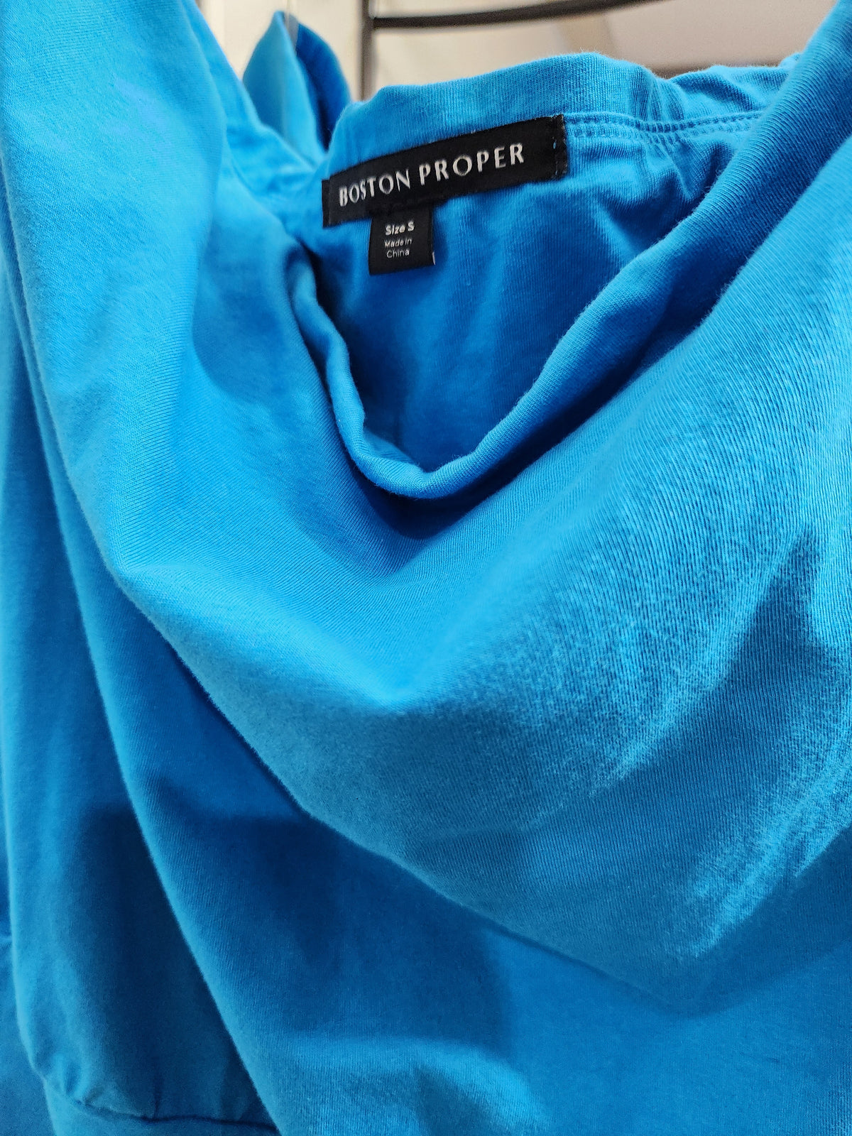 A close-up of a bright blue garment, likely a top or dress, showing the inner neck area with a visible Boston Proper brand label.