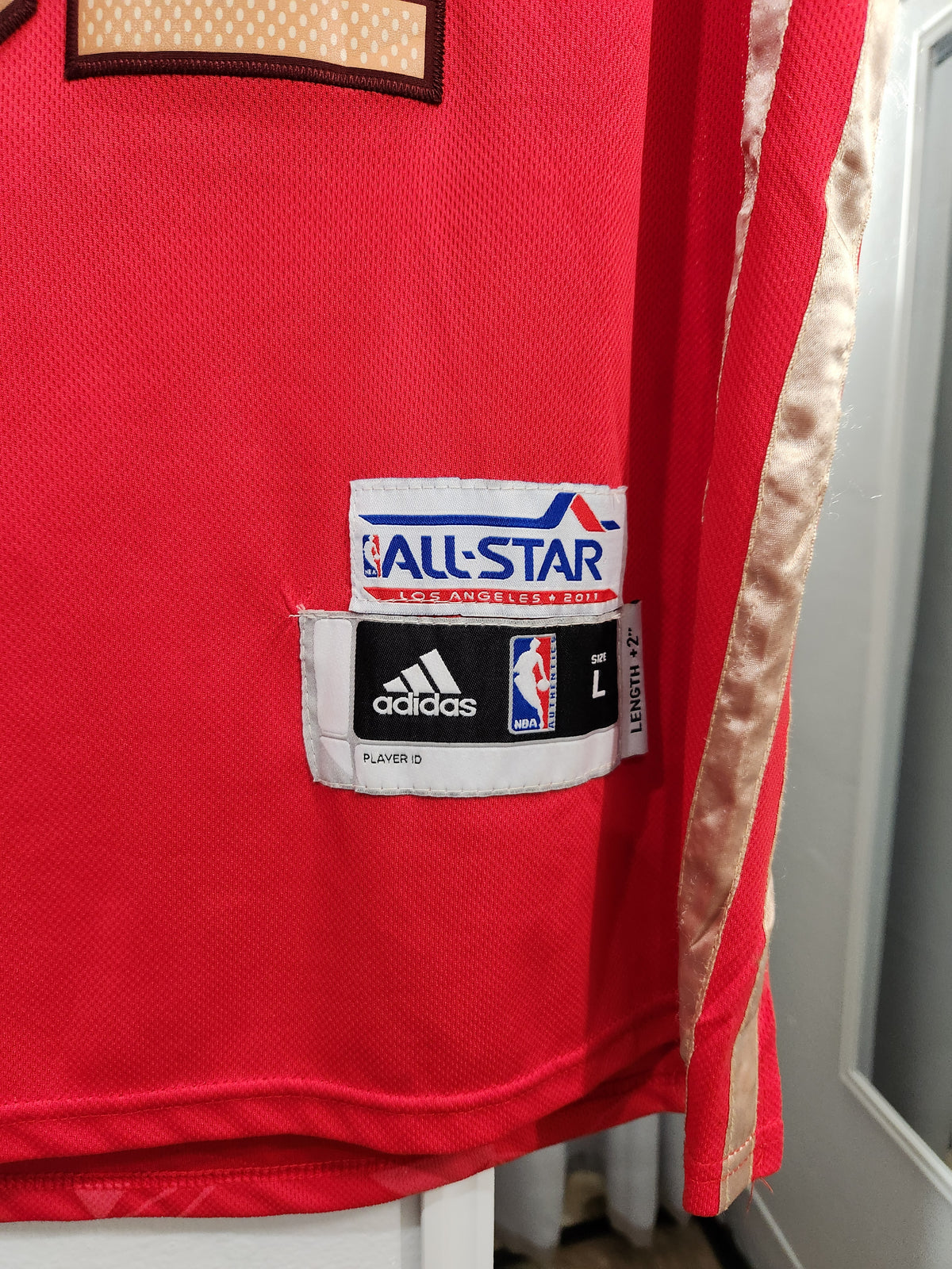 Close-up of a red Adidas basketball jersey showing the front patch area with an All-Star 2015 logo patch and the Adidas logo patch.