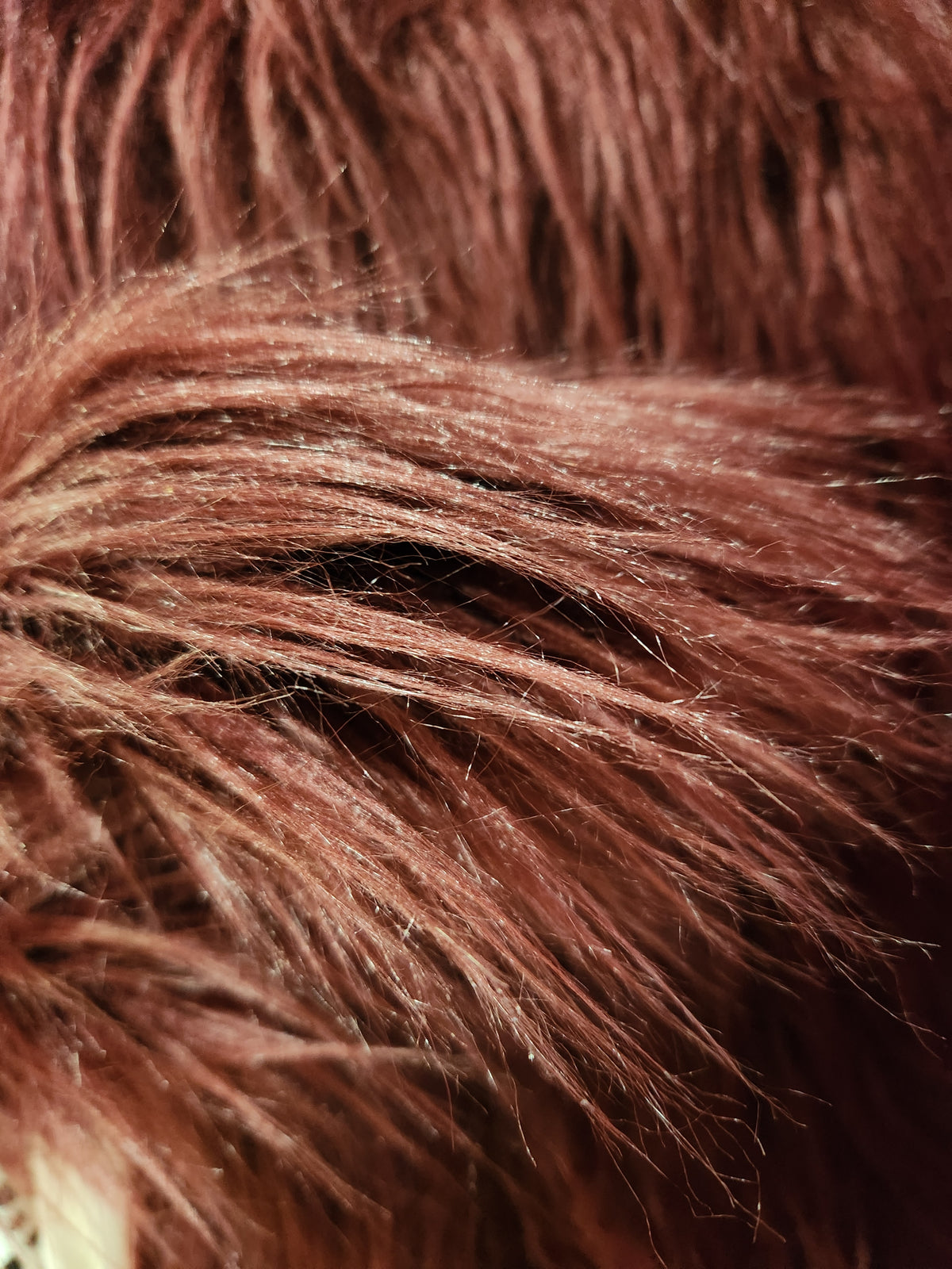A close-up texture shot of shaggy, reddish-brown faux fur or hair fibers.