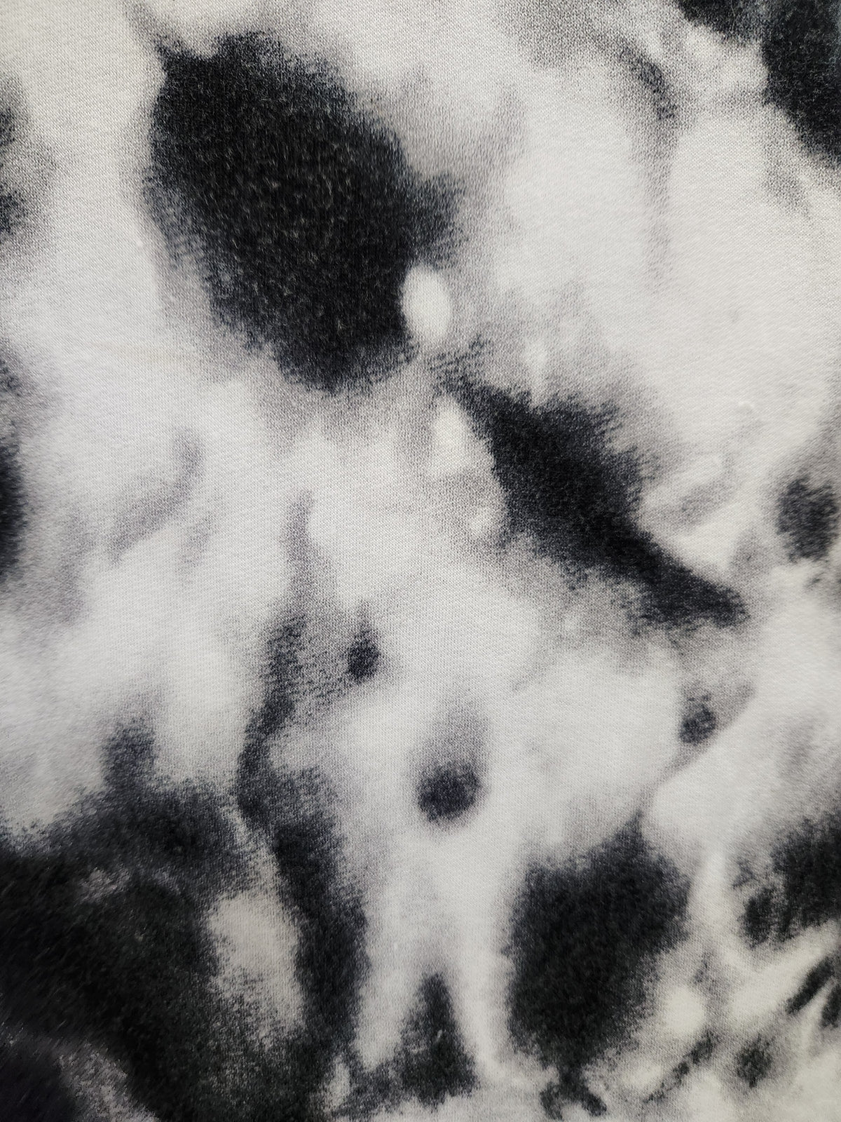 Black and white tie-dye patterned fabric texture closeup.