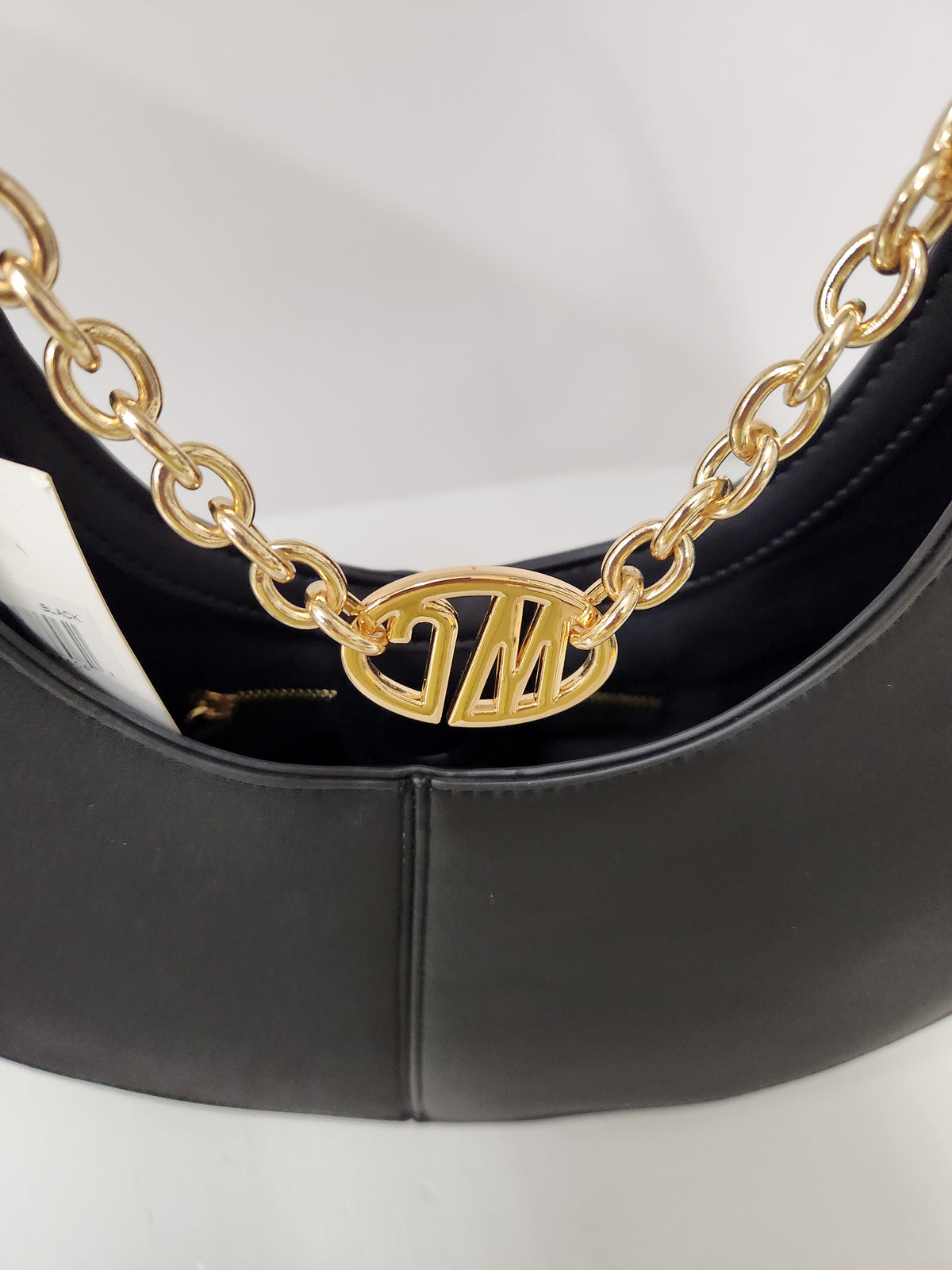 Close-up of a black leather handbag with a prominent gold chain strap and a gold interlocking 'JM' logo clasp.