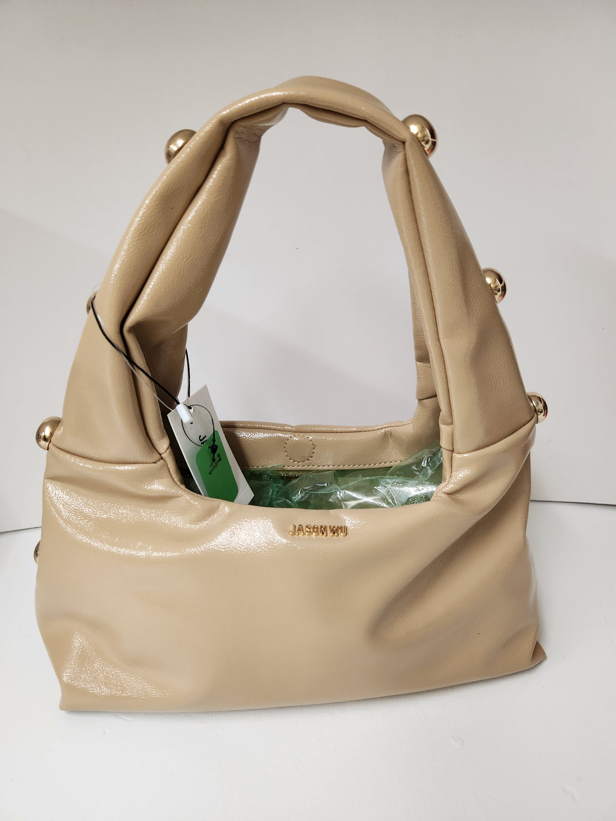 A beige leather shoulder bag with gold-tone hardware and a hangtag, shown on a plain white background.