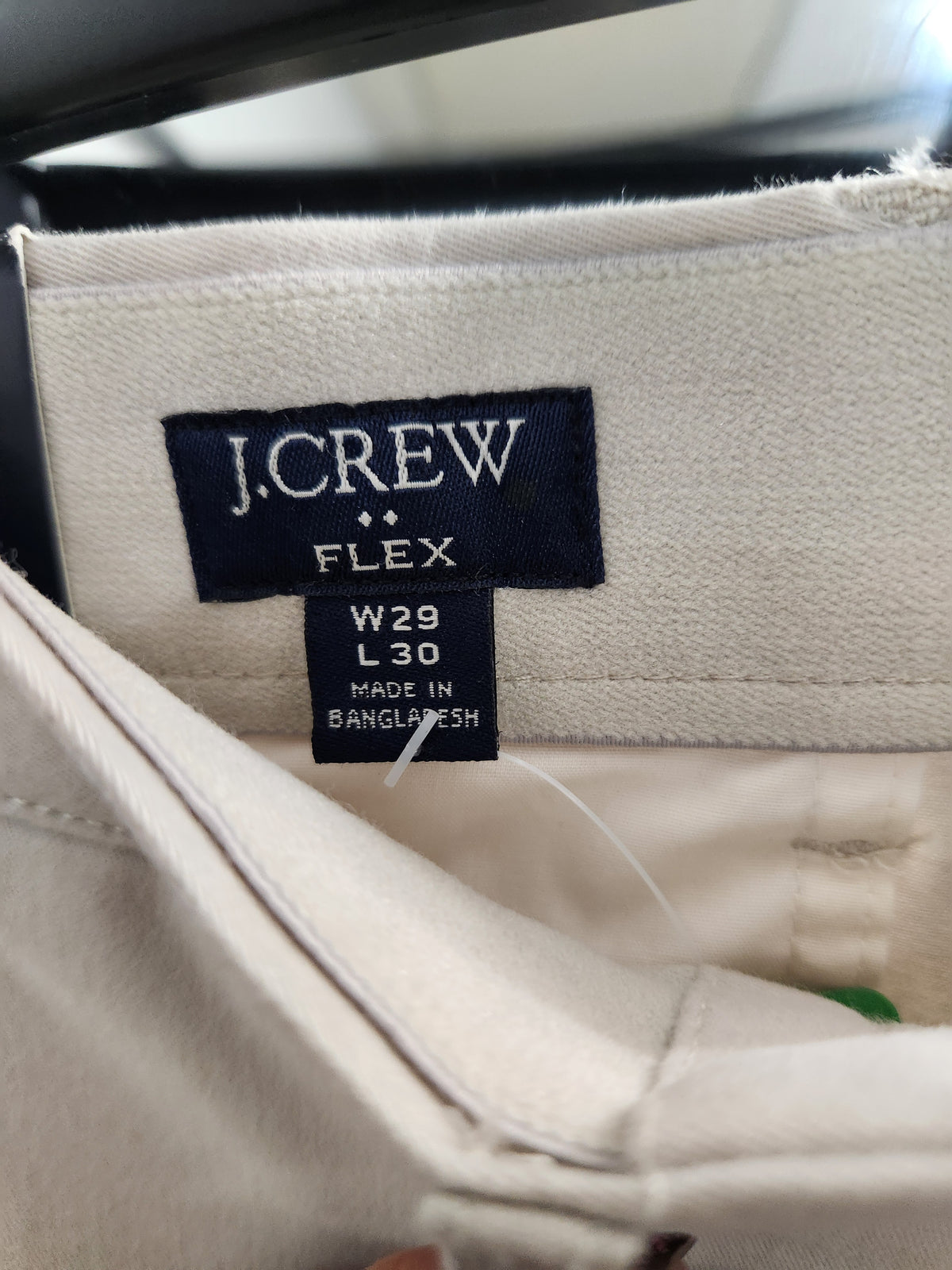 Close-up of the inside waistband of a J.Crew Flex pair of off-white trousers, showing the navy blue brand label and size information.