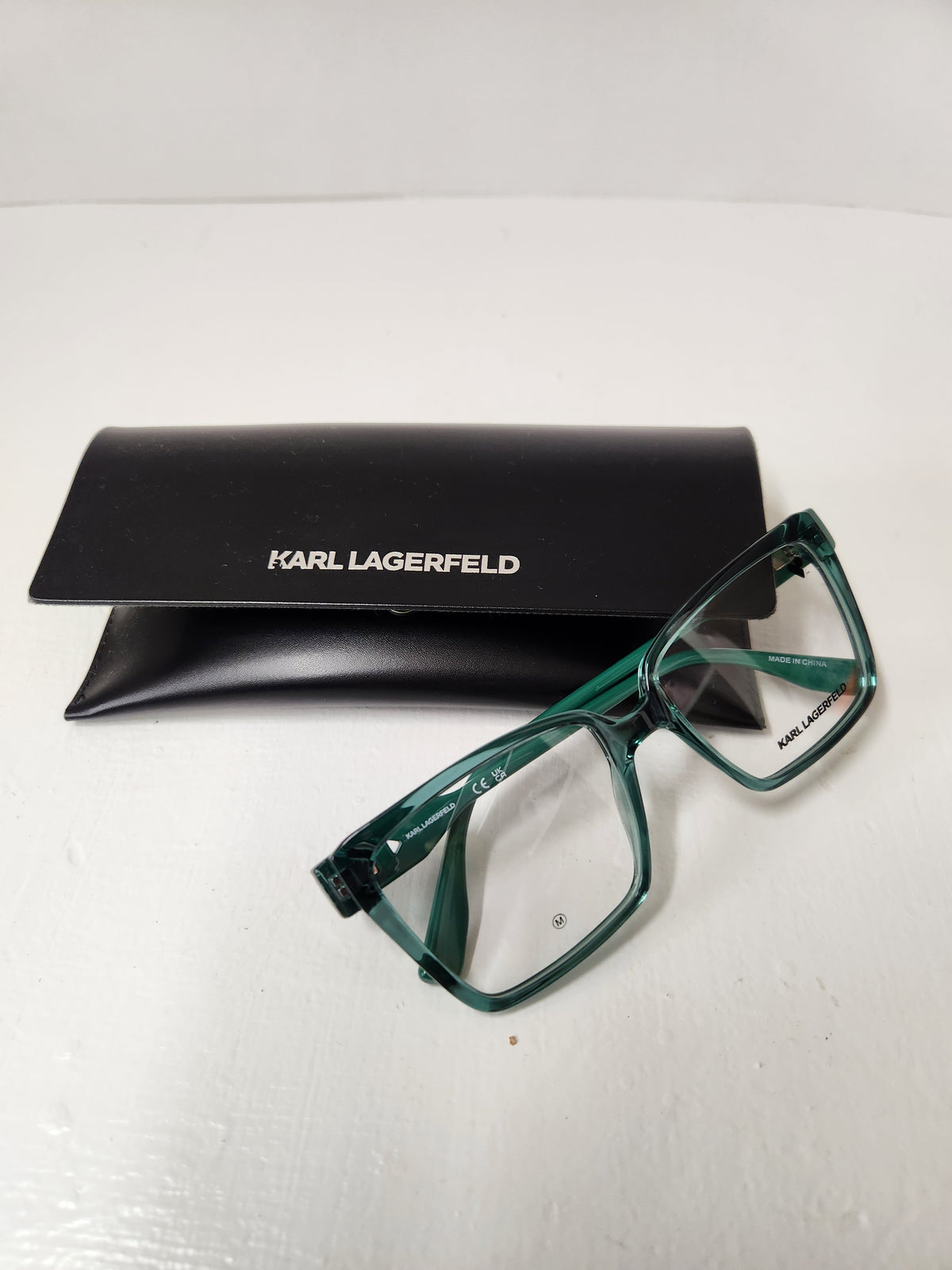 Karl Lagerfeld eyeglasses with a translucent green acetate frame, shown next to their black branded case on a white surface.