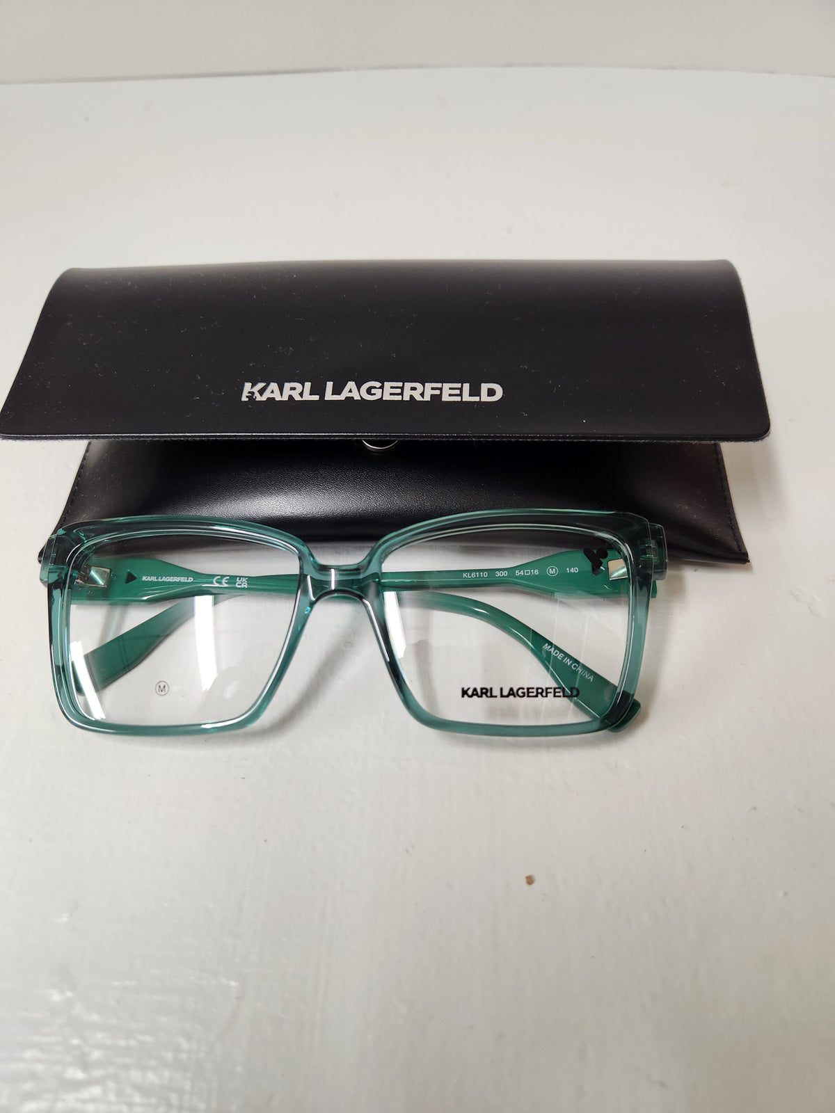 Karl Lagerfeld eyeglasses in translucent teal-green with a black case, displayed on a white surface.