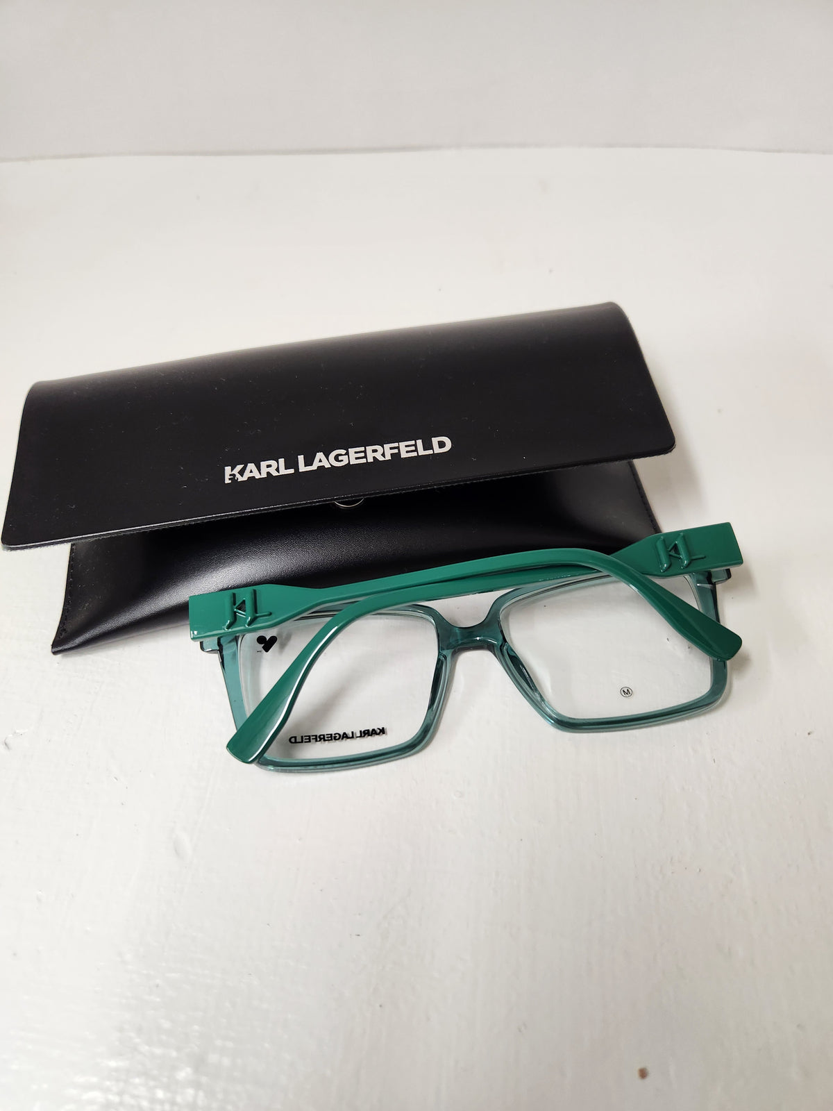 Karl Lagerfeld eyeglasses in translucent green with a matching black branded case, displayed on a white surface.