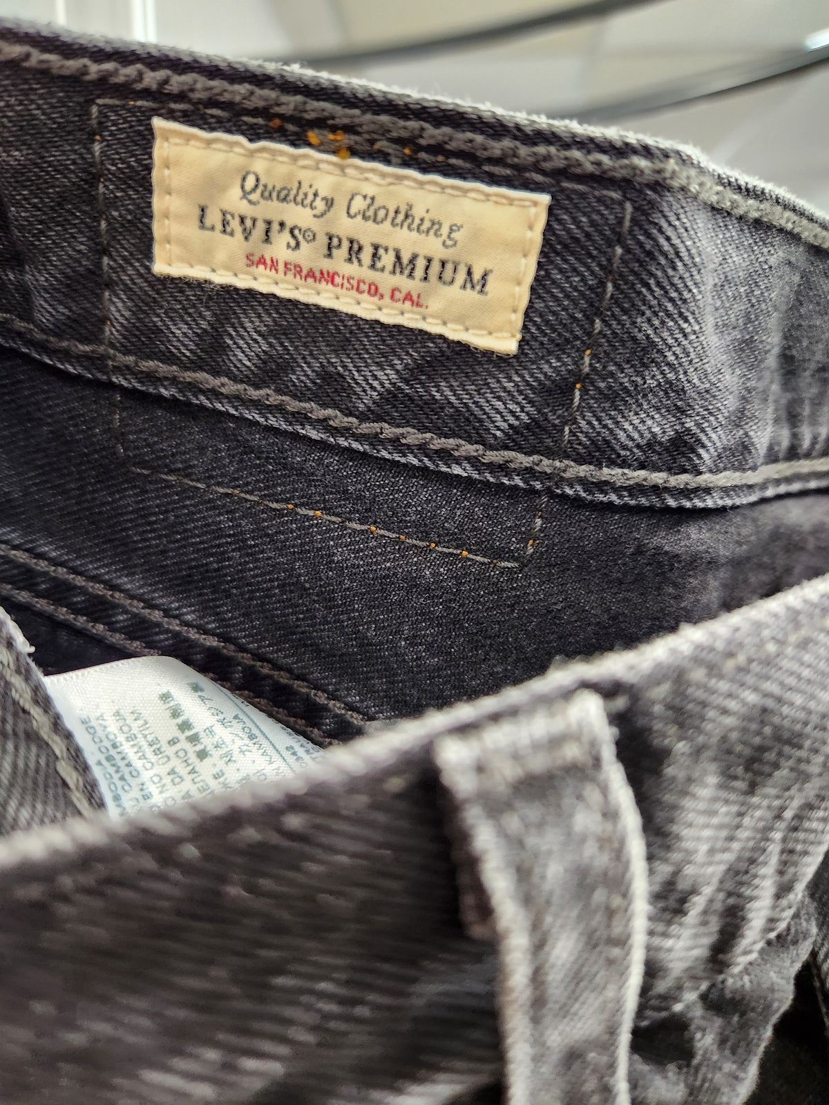 Close-up of the inside waistband of a pair of Levi's Premium jeans, showing the beige brand label and dark gray washed denim fabric.