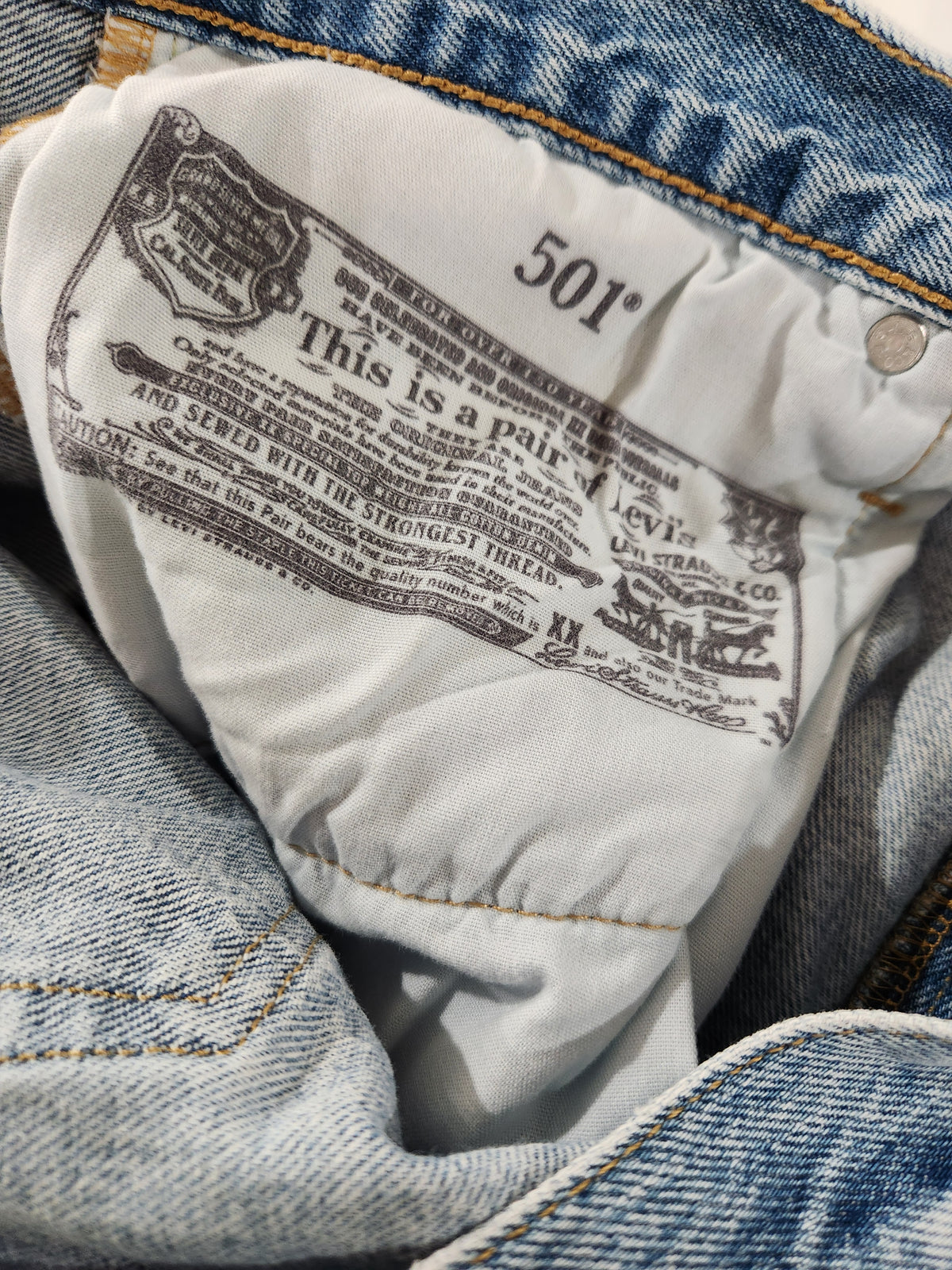 Close-up of the interior waistband label of a pair of blue Levi's jeans, showing the brand name, 'This is a pair of Levi's', and the size '501'.
