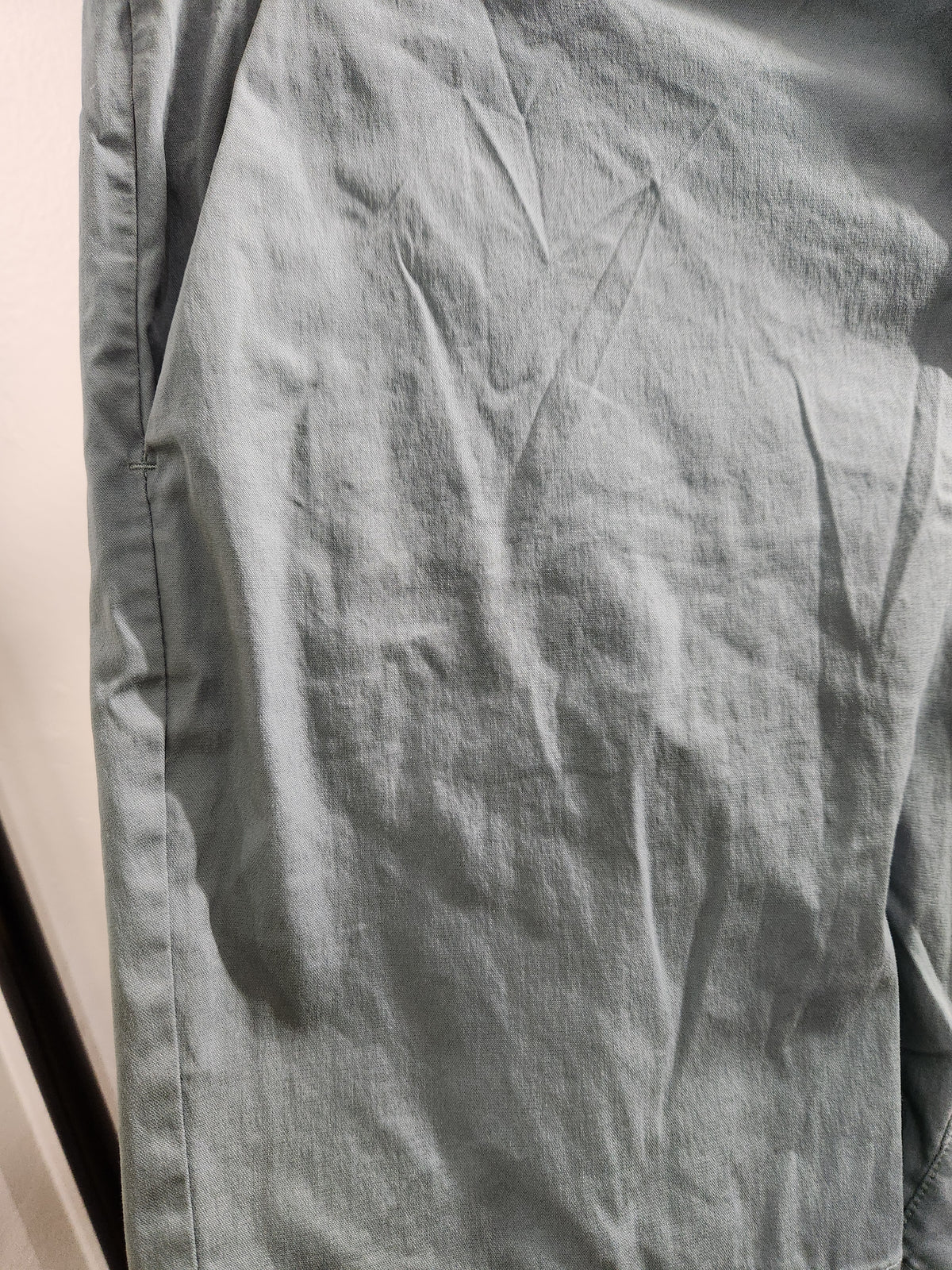 A close-up of a light gray fabric garment, showing the texture and folds of the material.