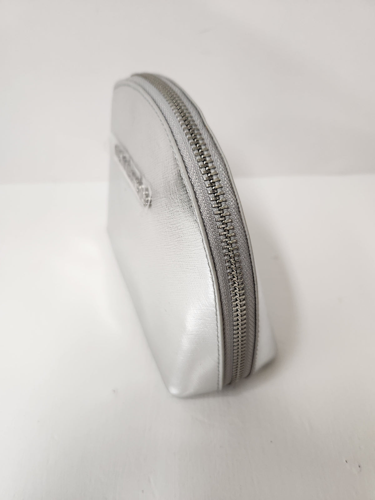 A small silver metallic zippered pouch or coin purse standing upright on a plain white surface.