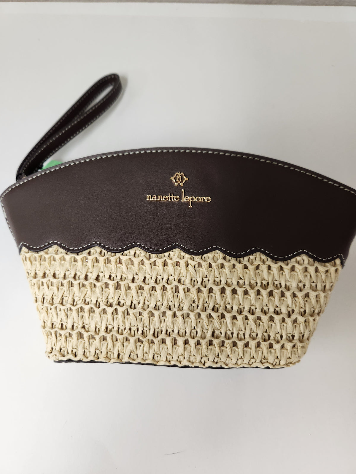 A woven clutch bag by Lanerie Josephson, featuring a dark brown leather top section with gold logo lettering and a scalloped edge, paired with a cream-colored woven body and a dark brown wristlet strap.