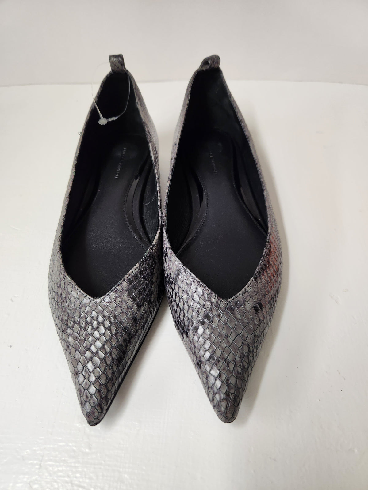 A pair of pointed-toe flats with a gray and black snakeskin pattern, photographed on a plain white surface.