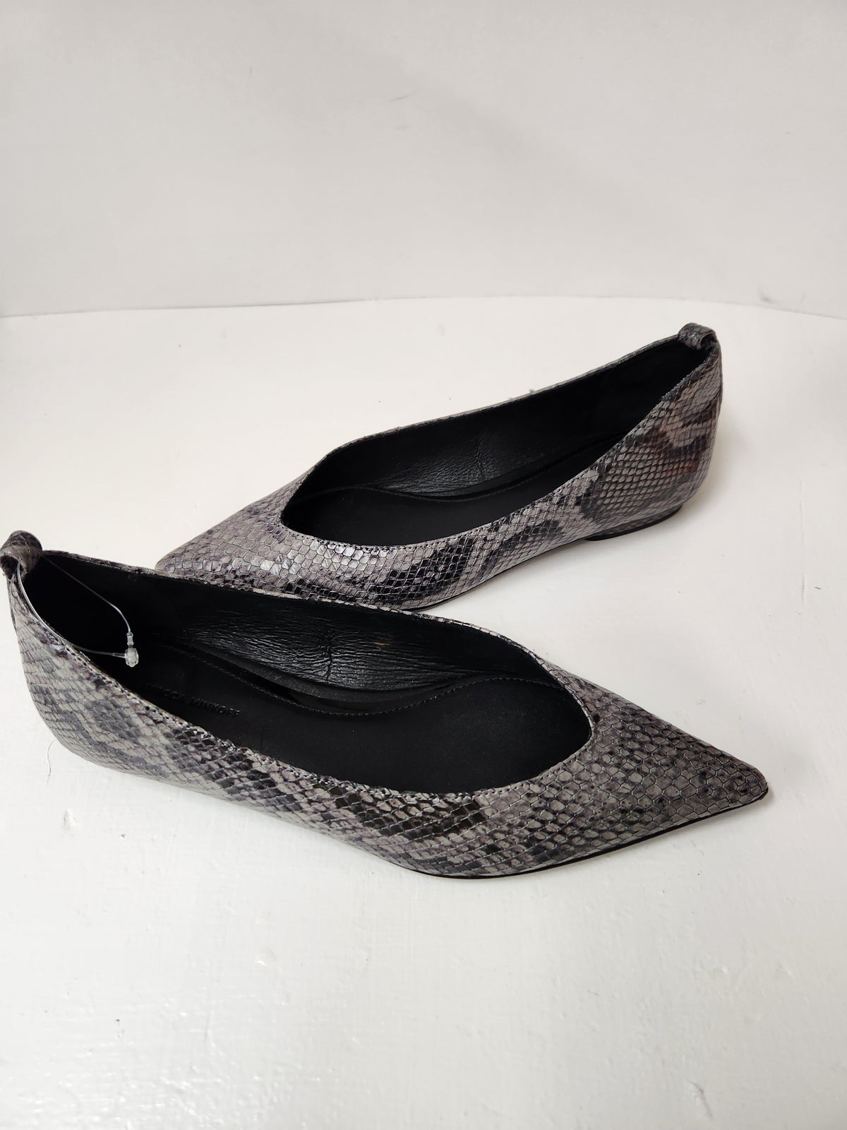 A pair of women's pointed-toe flats with a gray and black snakeskin pattern, displayed on a white surface against a white background.