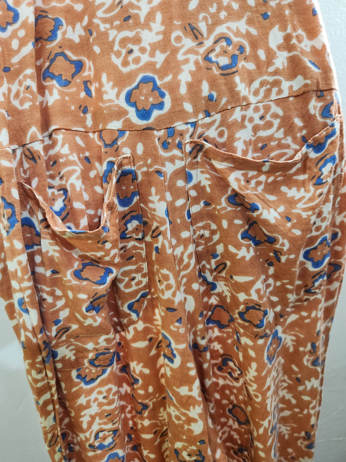 A close-up of a patterned garment, likely a skirt or dress, featuring a rust-orange, cream, and blue abstract floral print.