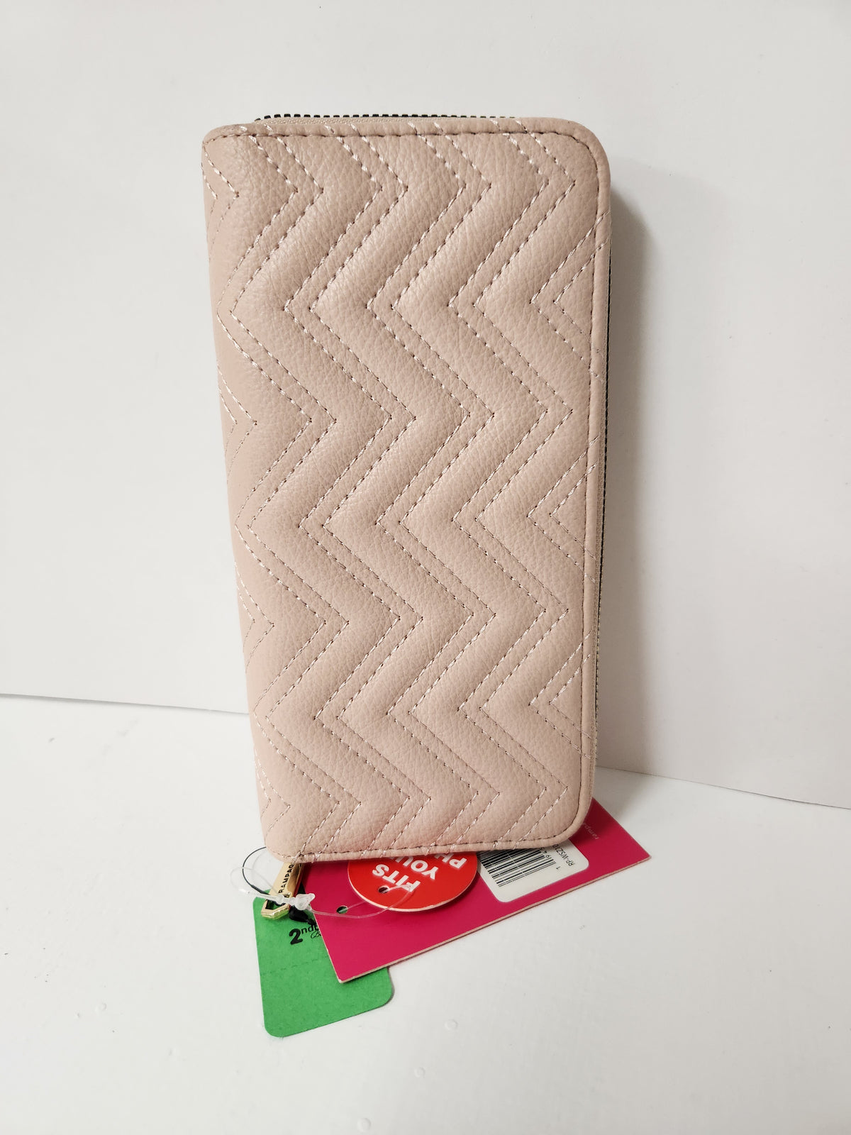 A light beige quilted zip-around wallet with a chevron pattern, standing upright on a white surface with its retail tags attached.