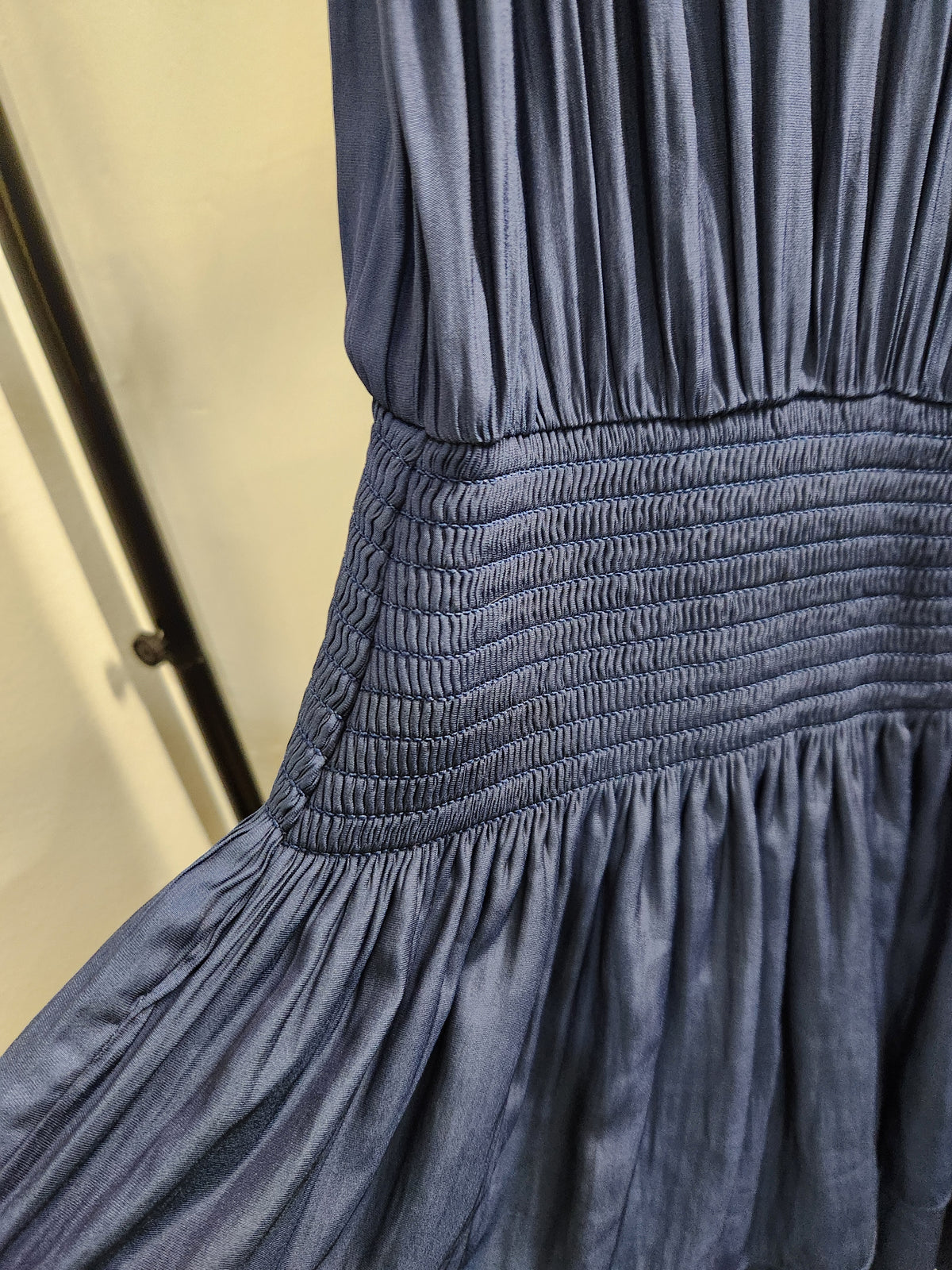 Close-up of a slate blue dress with a smocked elastic waistband and gathered skirt.