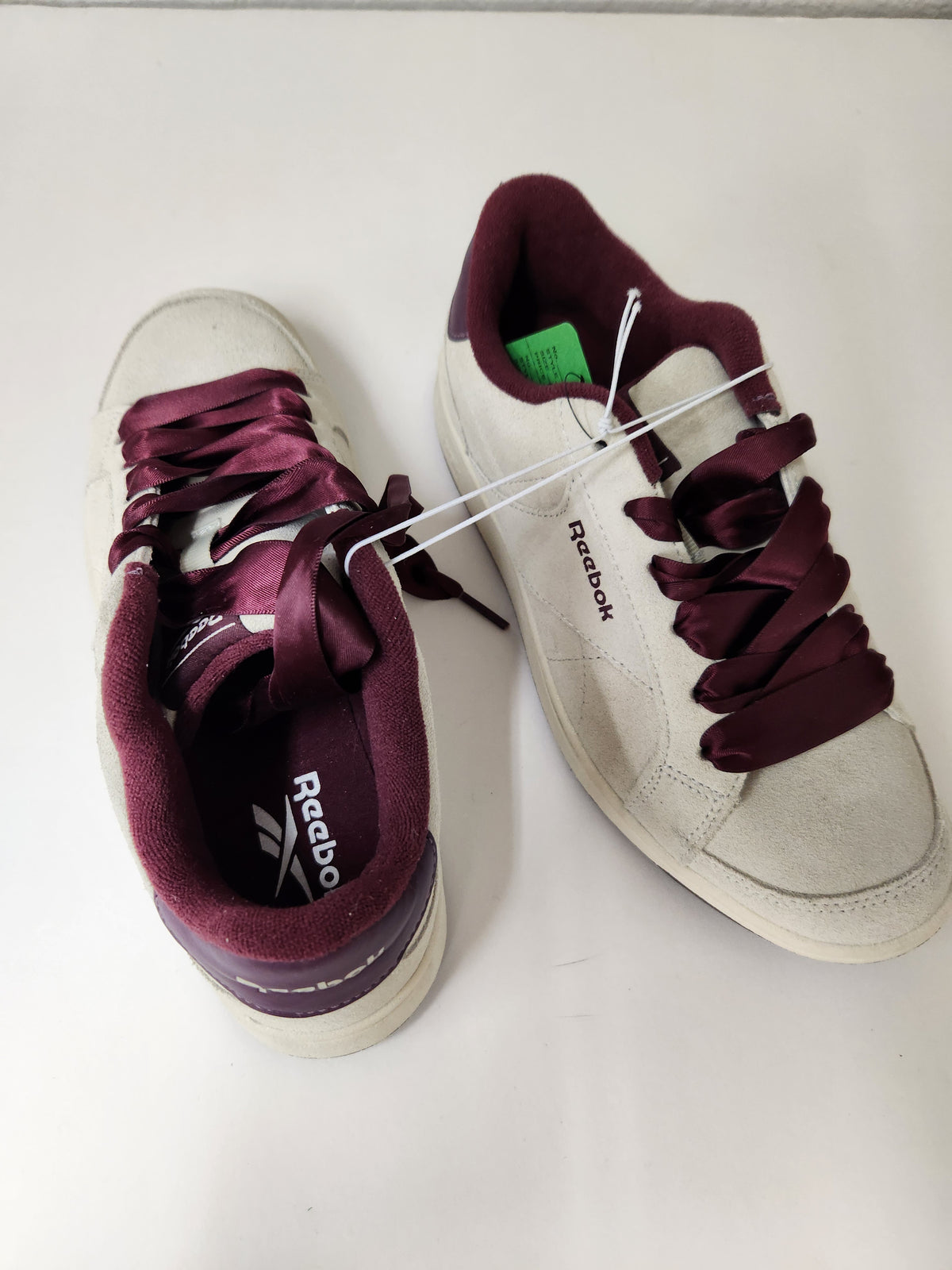 A pair of Reebok sneakers in off-white suede with deep burgundy laces and matching burgundy lining, shown on a plain light background.