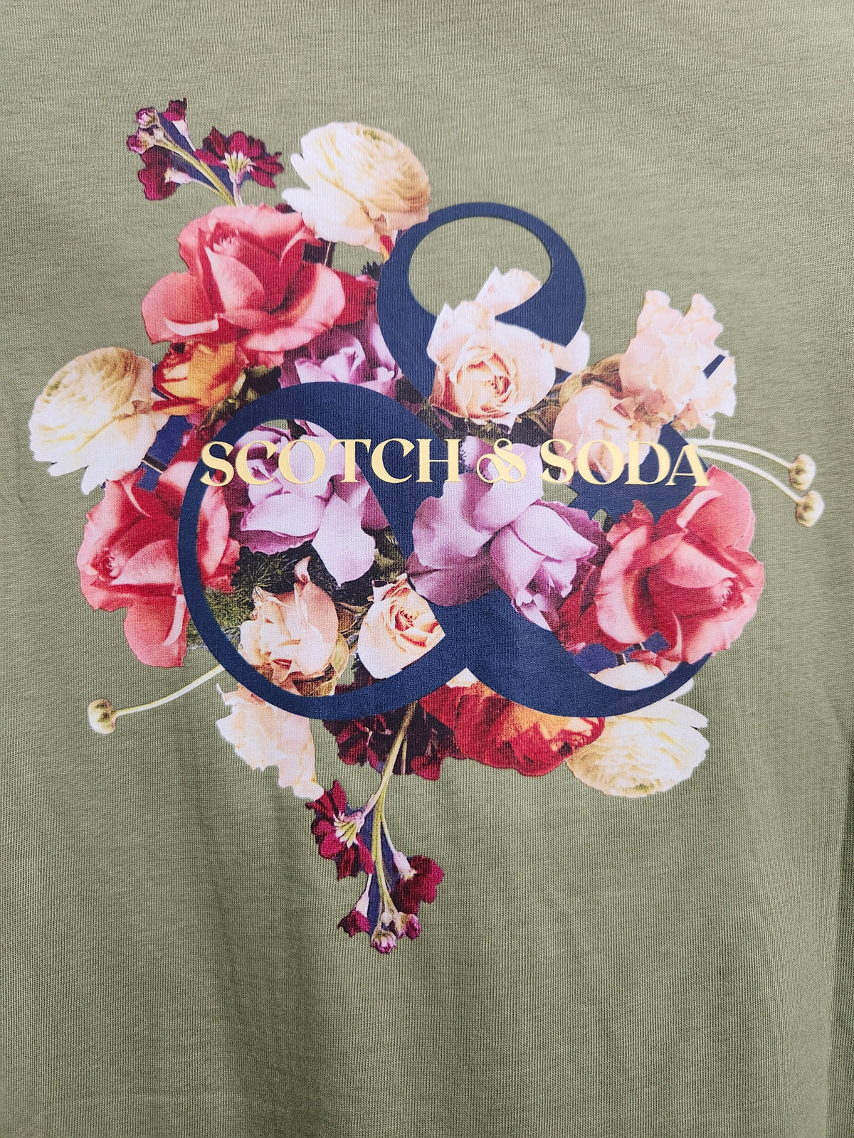 Olive green t-shirt featuring a large graphic print of a floral bouquet with pink, red, and cream roses, overlaid with a dark blue ampersand and the text 'SCOTCH'S SODA' in gold.