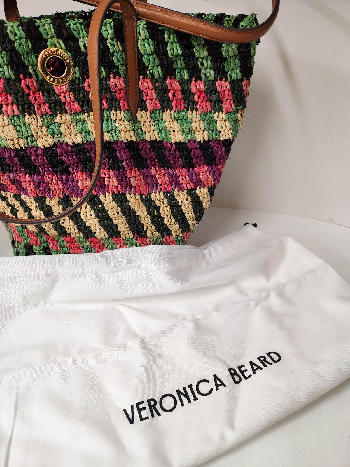 Veronica Beard Striped Raffia tote bag or anchor basket tote. A hand-woven multi-colored raffia body with dual brown leather top shoulder handles and a small golden medallion toggle closure at the top. Dust Bag included