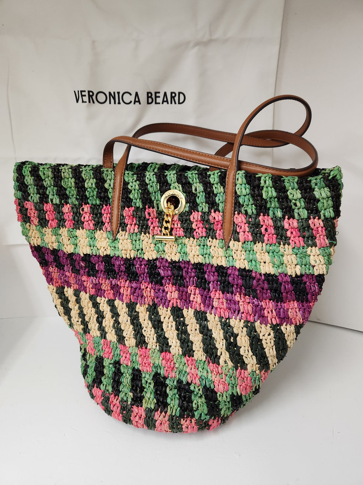 Veronica Beard Striped Raffia tote bag or anchor basket tote. A hand-woven multi-colored raffia body with dual brown leather top shoulder handles and a small golden medallion toggle closure at the top. Dust Bag included