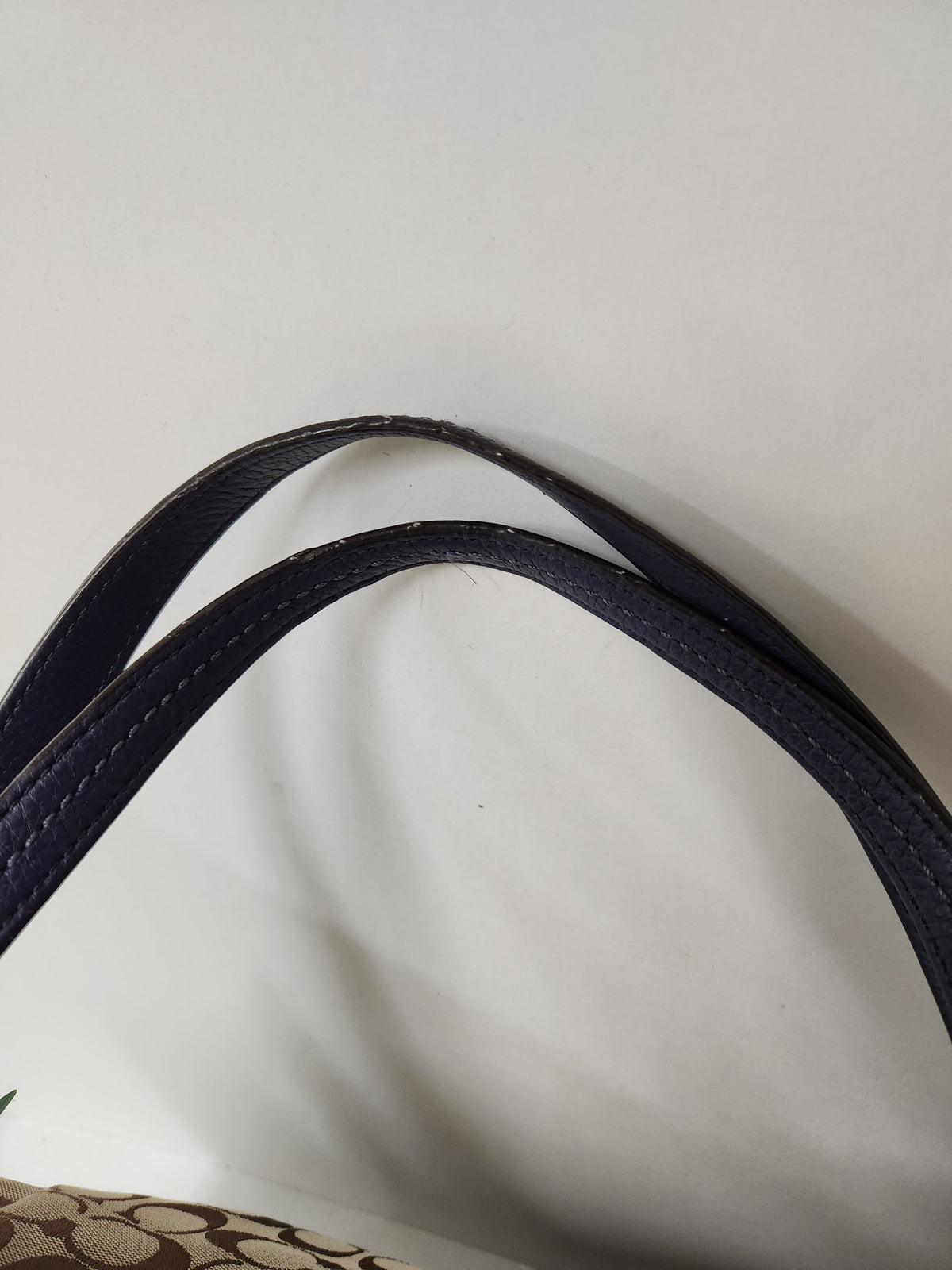 Close-up of a dark navy blue leather strap with visible wear and scuffing on a light gray background.