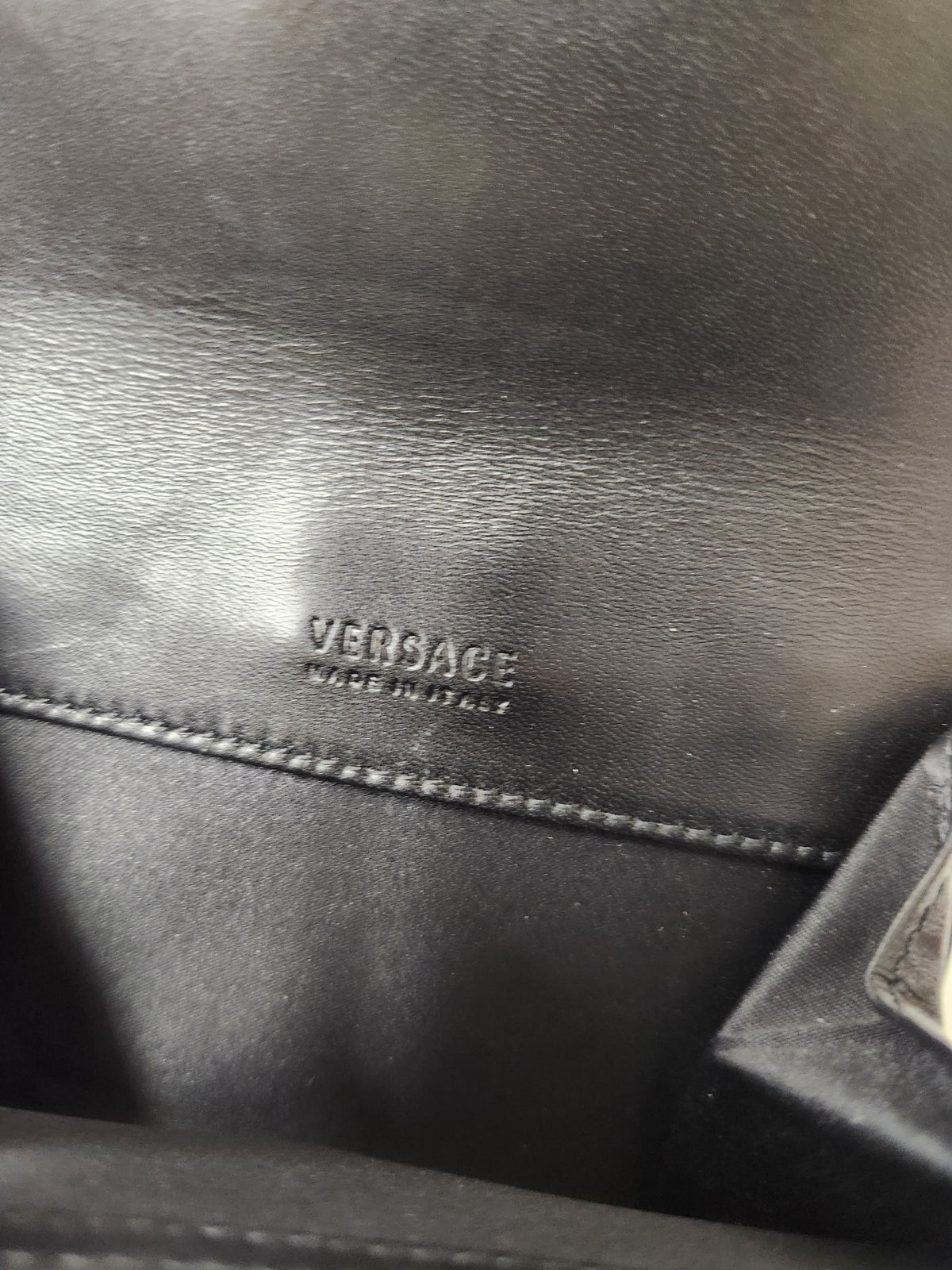Close-up of black leather interior with an embossed Versace logo and 'MADE IN ITALY' text.