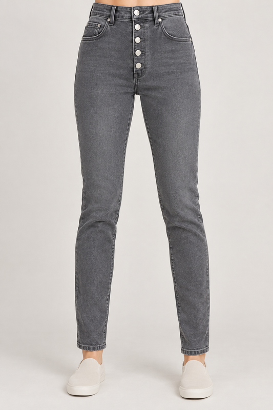 A person wearing dark gray slim-fit jeans with a high waist and a front button fly, paired with white slip-on shoes, shown against a light gray studio background.